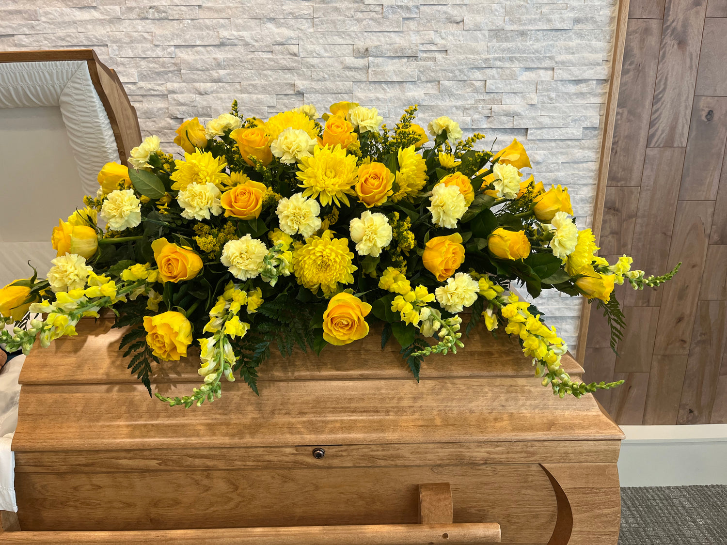 Yellow casket spray with seasonal flowers