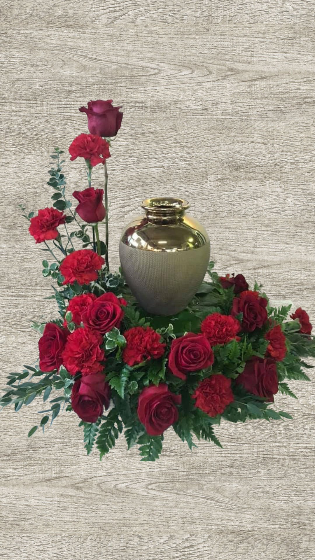 Red rose and carnation urn arrangement with greenery