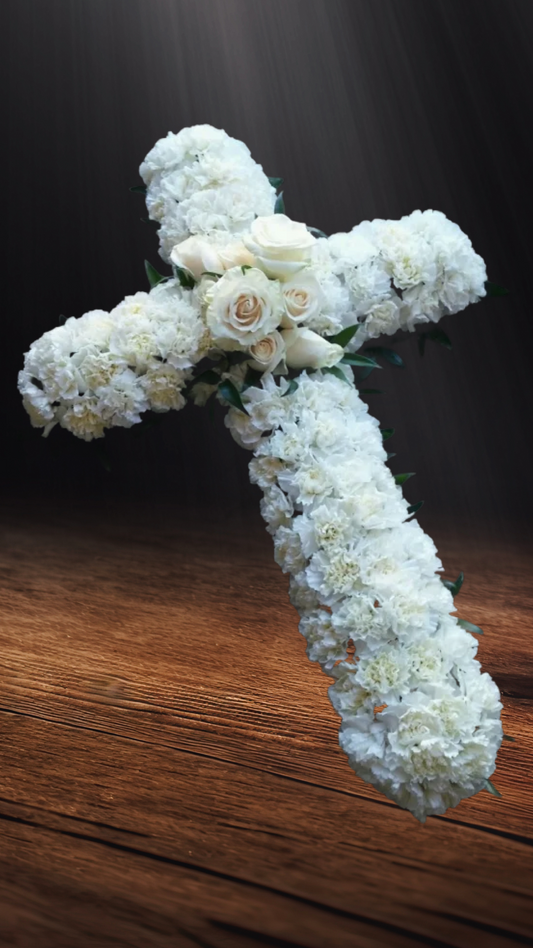 Croix suspendue de œillets blancs et de roses
