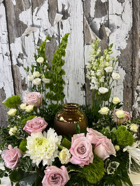 Soft pink rose urn arrangement with white flowers, bells of Ireland, and greenery