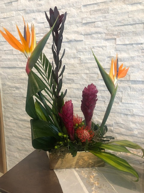 Tropical funeral arrangement with bird of paradise, red ginger, and fresh foliage