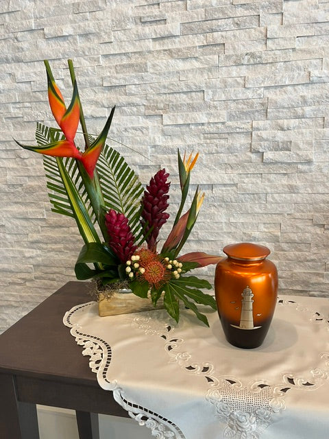 Tropical urn arrangement with bird of paradise, ginger, and greenery beside an urn