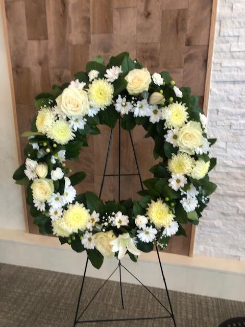 White and cream funeral wreath with roses, mums, daisies, and greenery