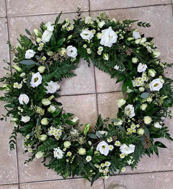 White funeral wreath with lisianthus, daisies, ferns, and mixed greenery