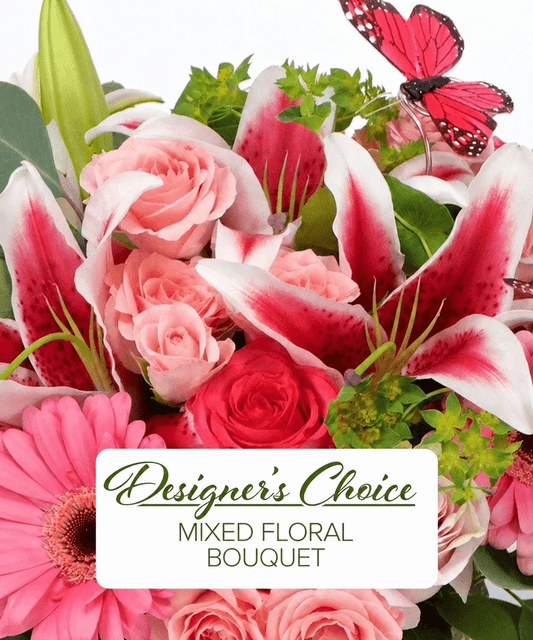 A mixed floral bouquet featuring pink roses, pink-and-white lilies, pink gerbera daisies, green foliage, and a red butterfly decoration, with a white label reading 'Designer's Choice Mixed Floral Bouquet'.
